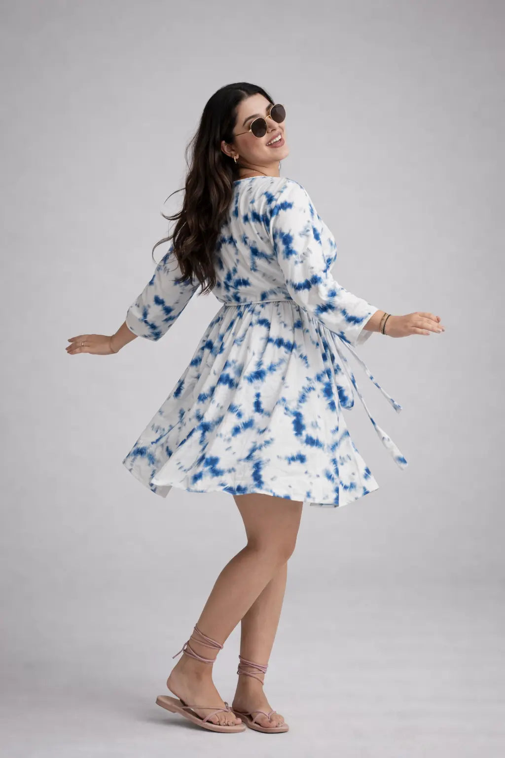 Woman wearing a tie-dye dress on a plain background